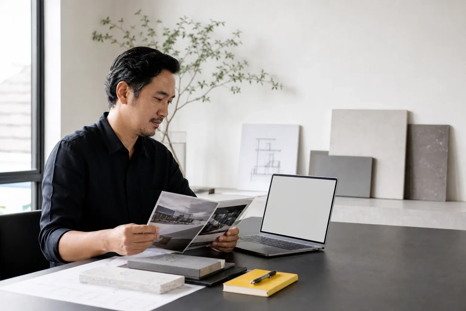A professional studio founder reviewing company materials beside a laptop
